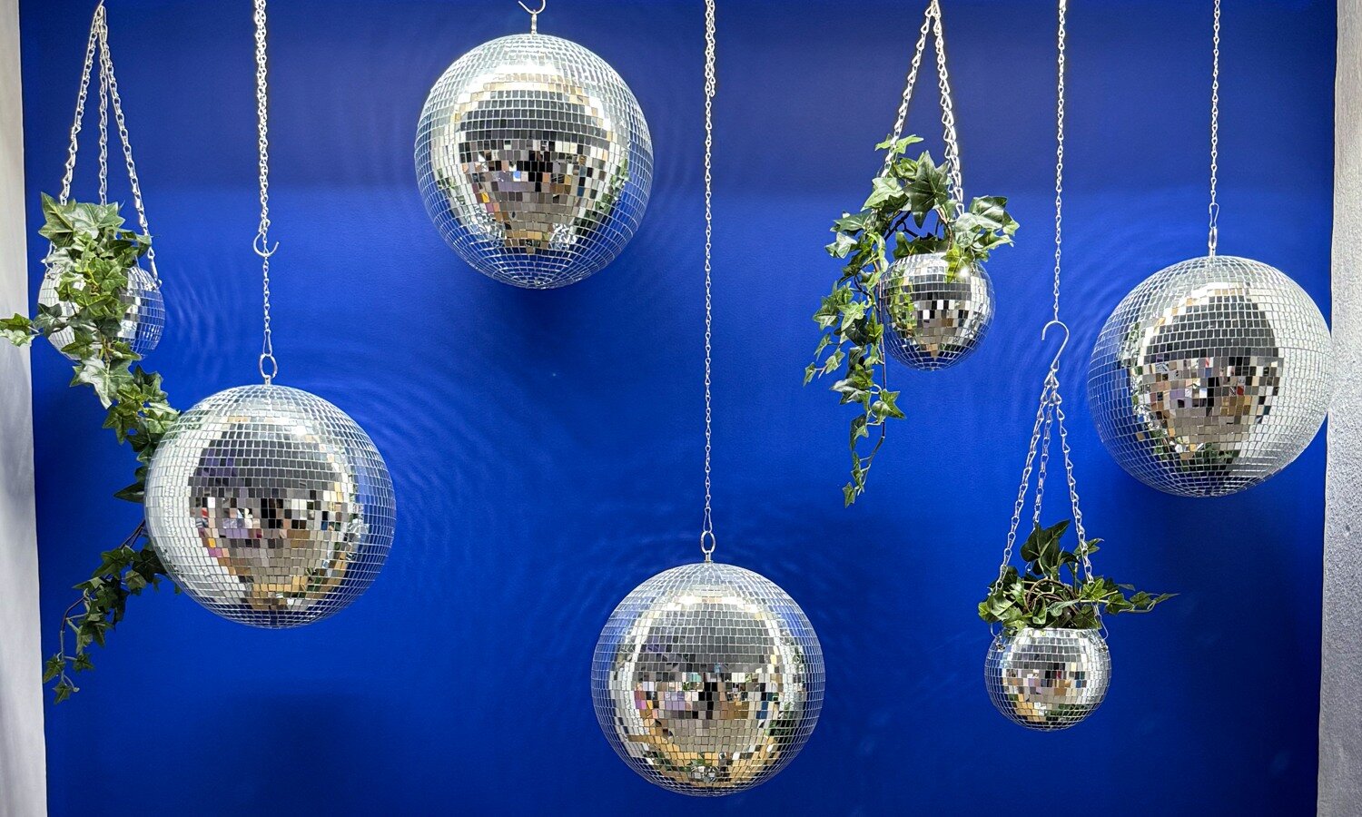 Hanging planters and disco balls against a blue background.