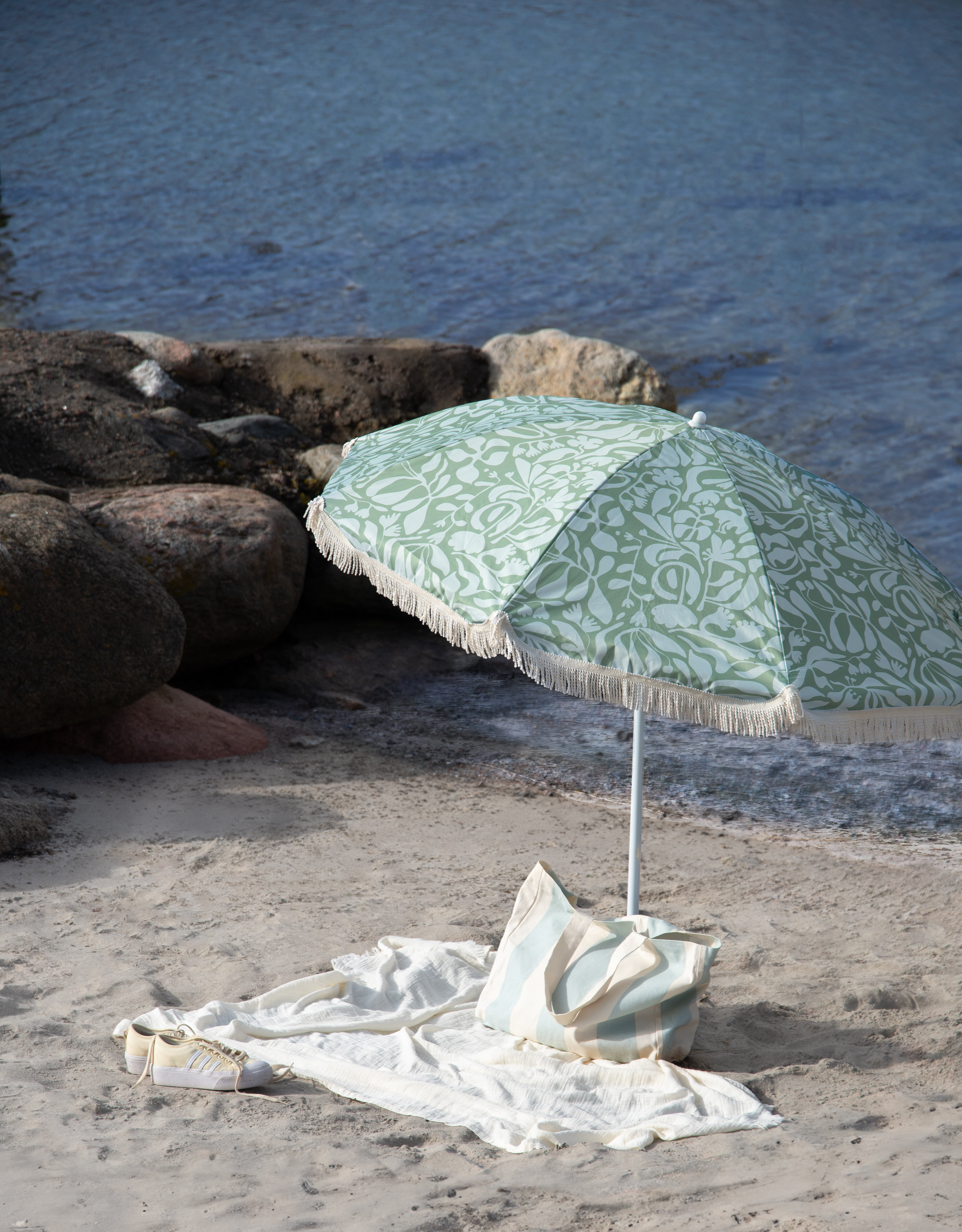 Parasol and blanket set up on cliffs by the sea.
