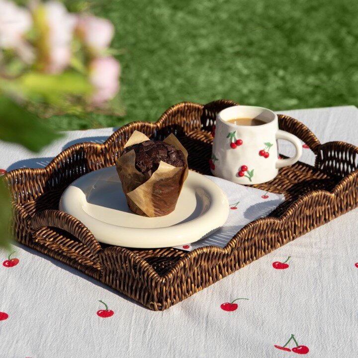 White mug with red cherry pattern on a wooden table, surrounded by fresh cherries