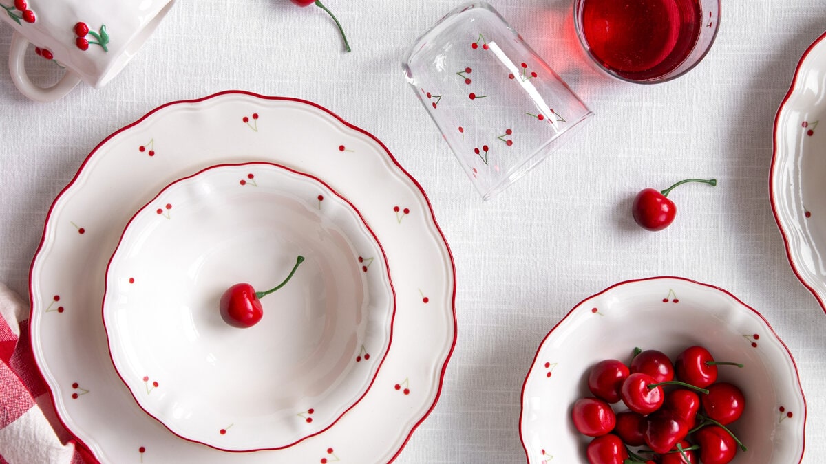 Bedside table with a table lamp, a mobile phone, and stacked books with a decorative jar on top.