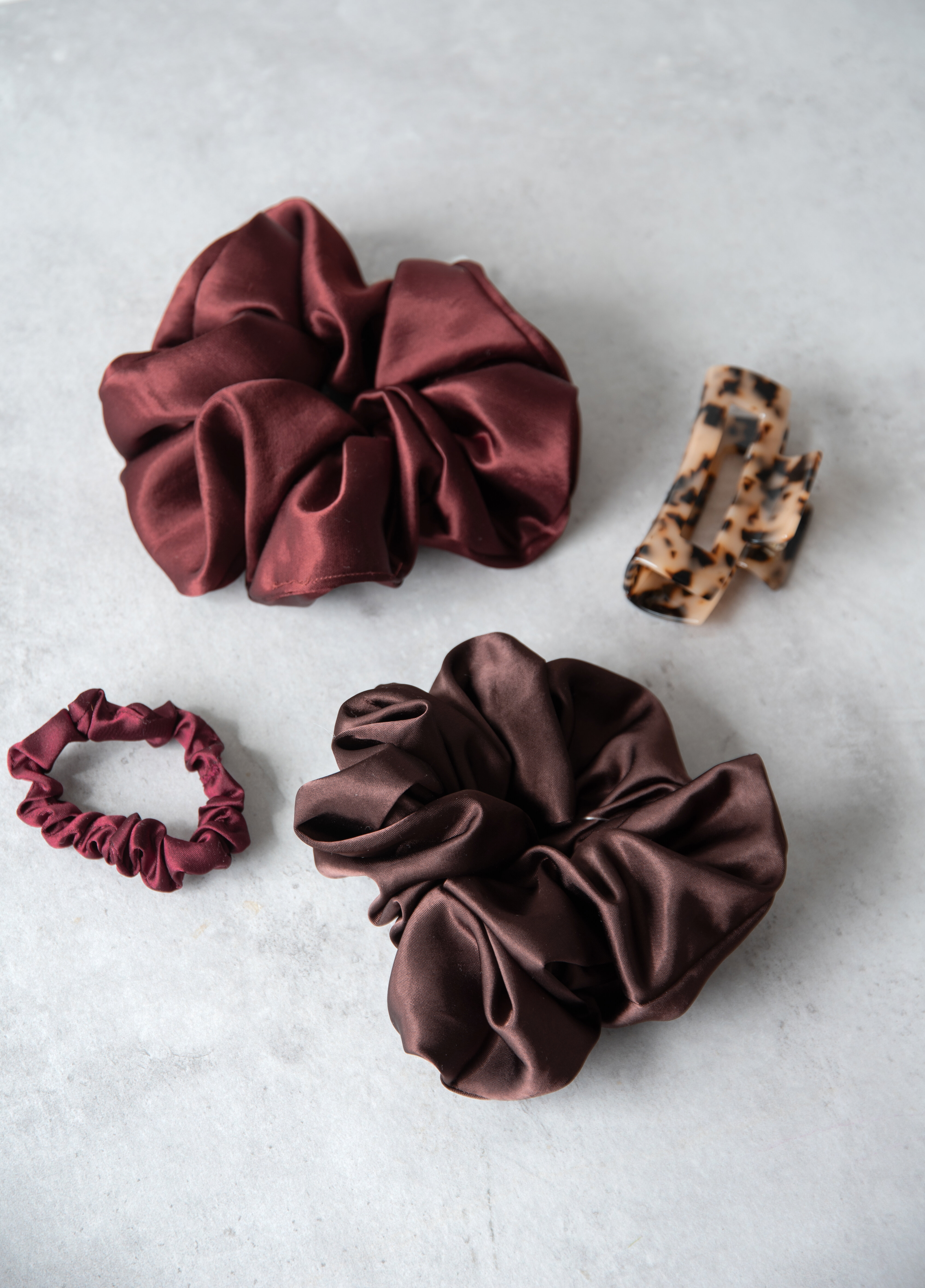 Hair accessories featuring scrunchies and claw clips in various colours and patterns.