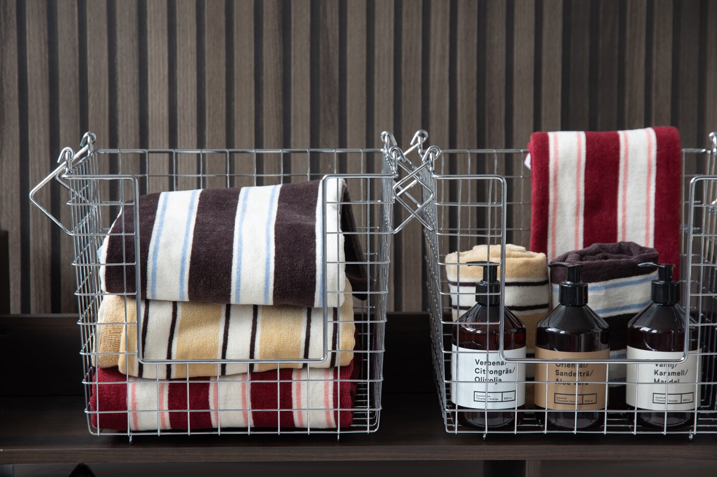 Striped towels, wire storage baskets, and hand soaps styled together as inspiration for bathroom storage and organization.