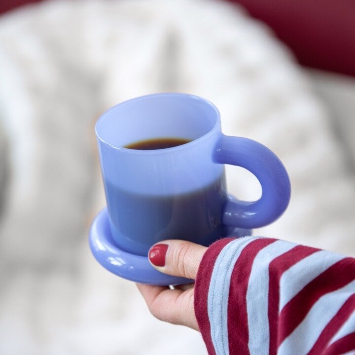 Blue mug held in a hand as a gift for a teacher.