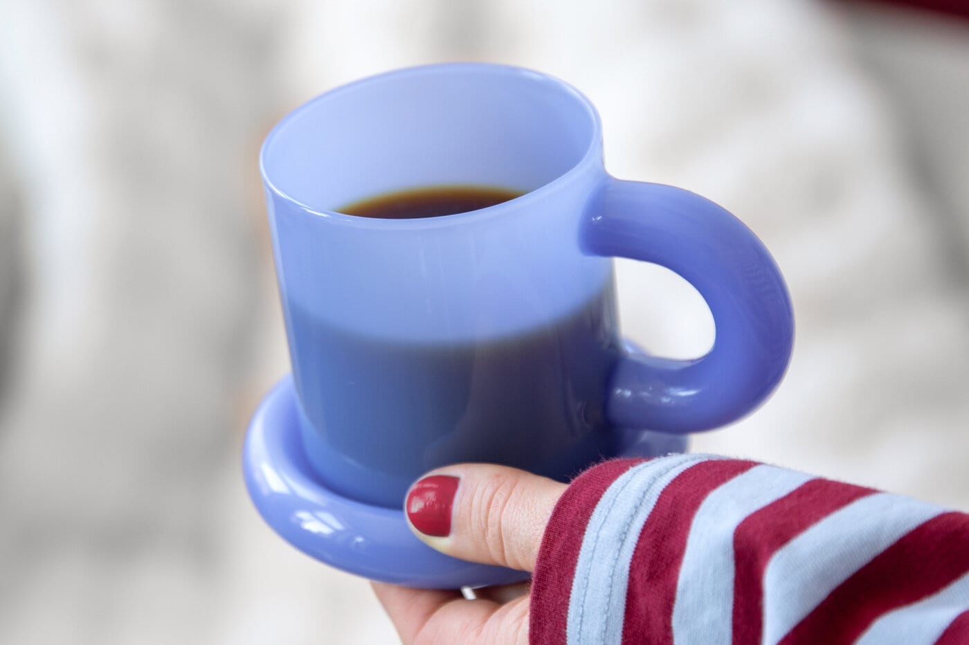 Person holding a blue mug with matching saucer