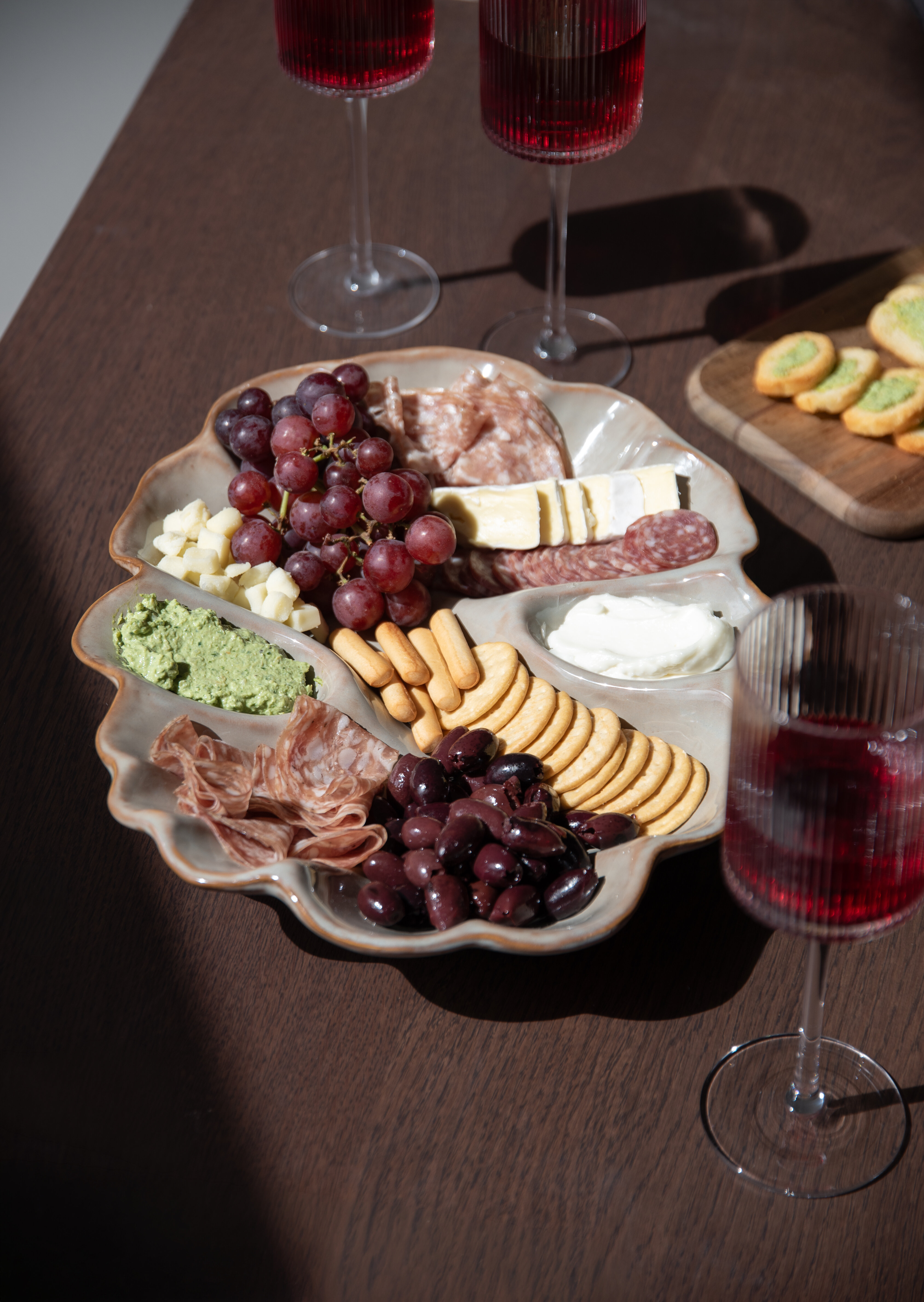 Serving platter with cheese, charcuterie, grapes, crackers and other accompaniments