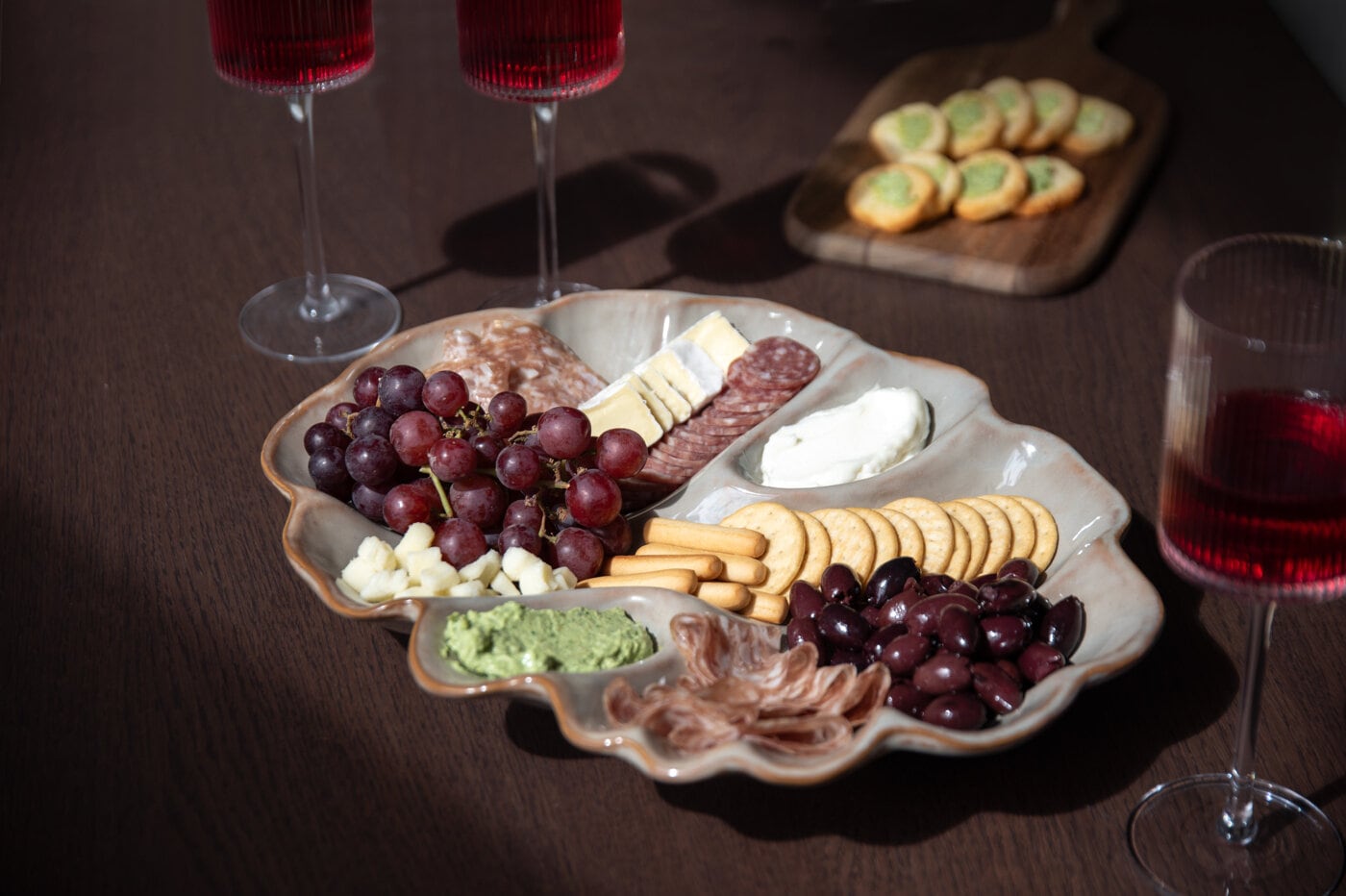 Serving platter with cheese, charcuterie, crackers, and grapes, styled as inspiration for dinner gatherings and gift ideas.