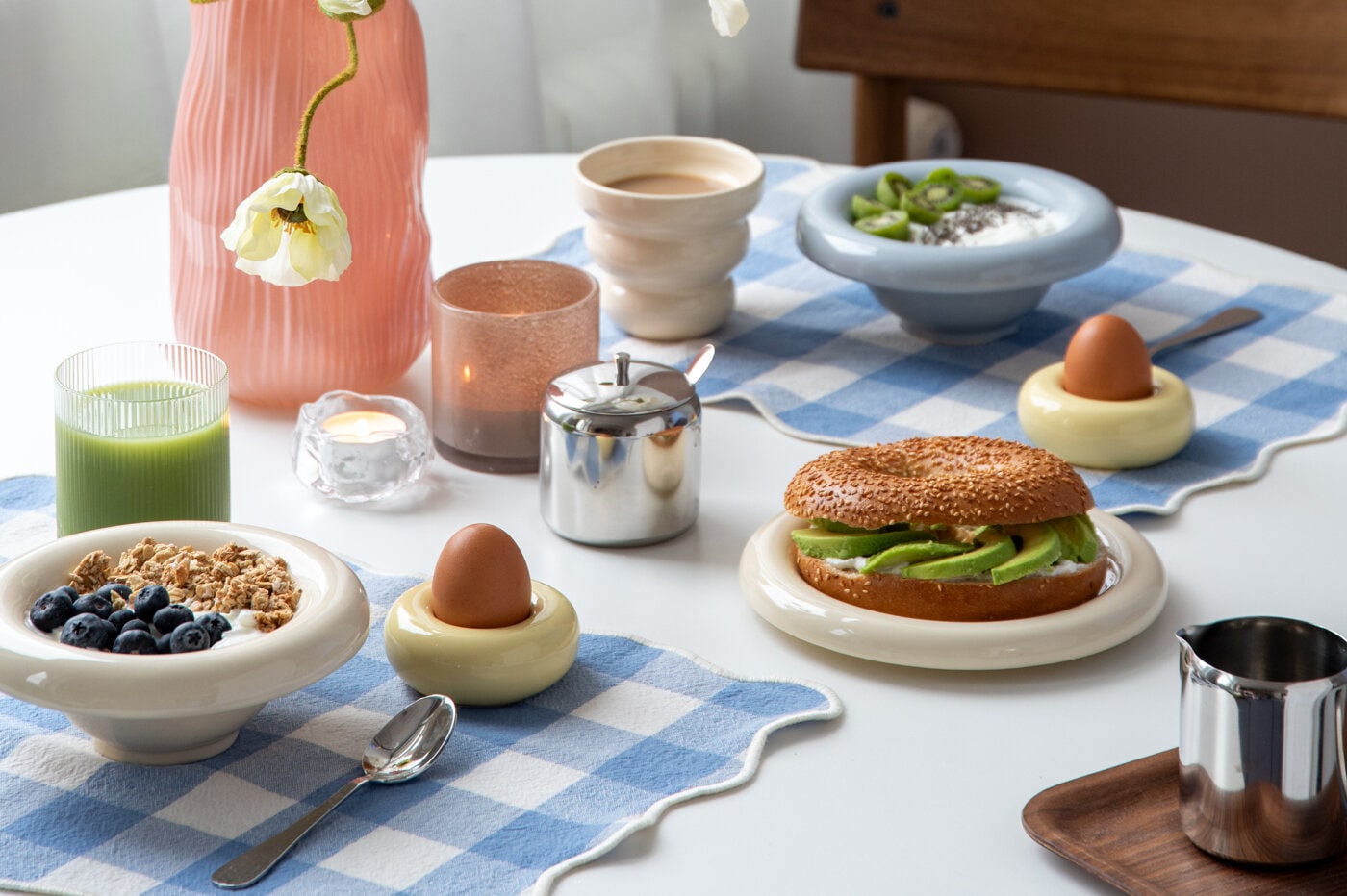 Breakfast served in a light blue, rounded bowl with a ribbed glass on a blue checkered placemat.