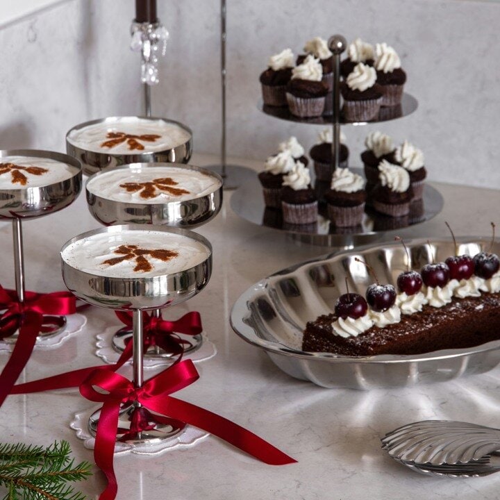 Christmas table setting with cakes and pastries on stands decorated with red ribbons.