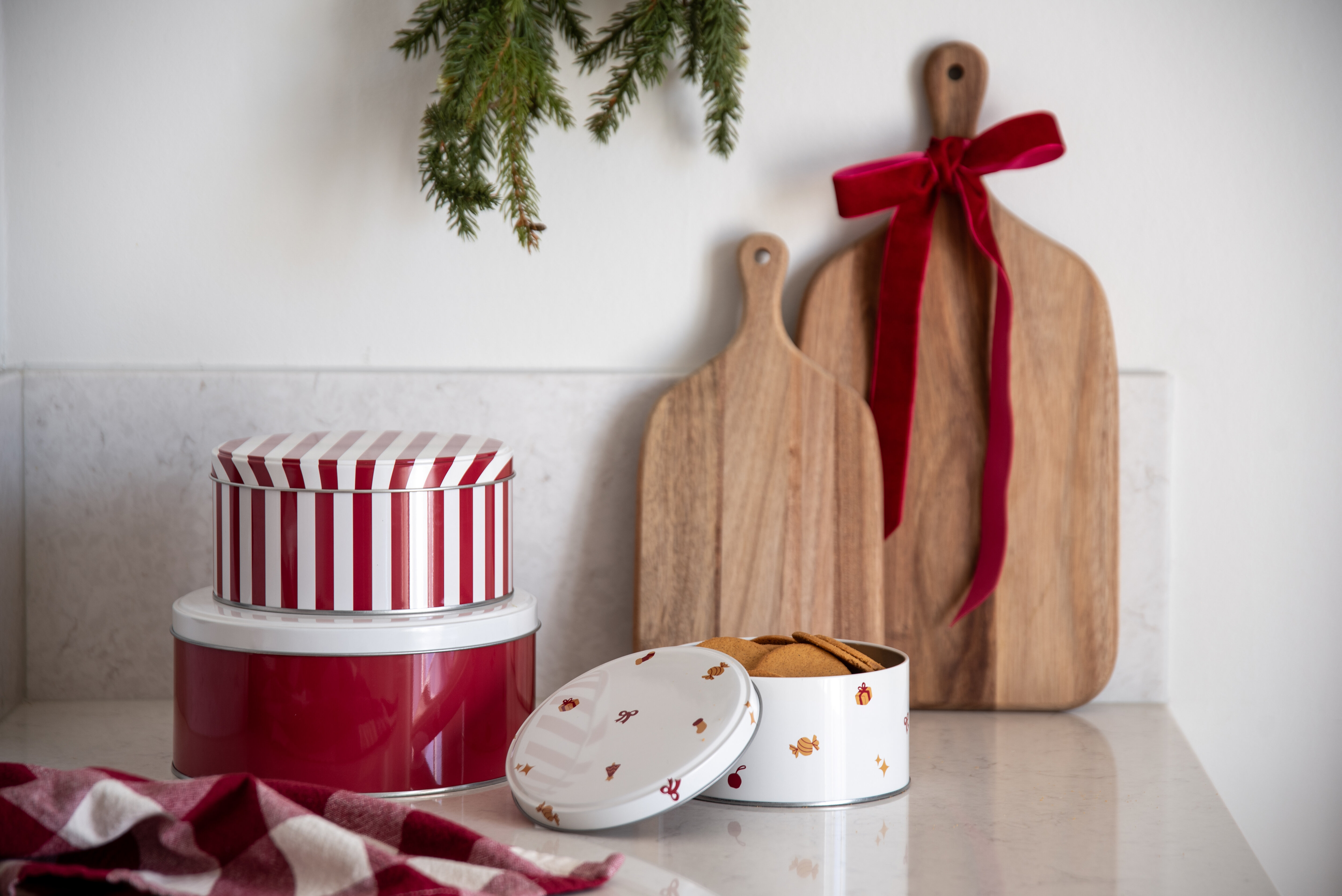 Christmas cookie tins and chopping boards decorated with a red bow and fir branches.