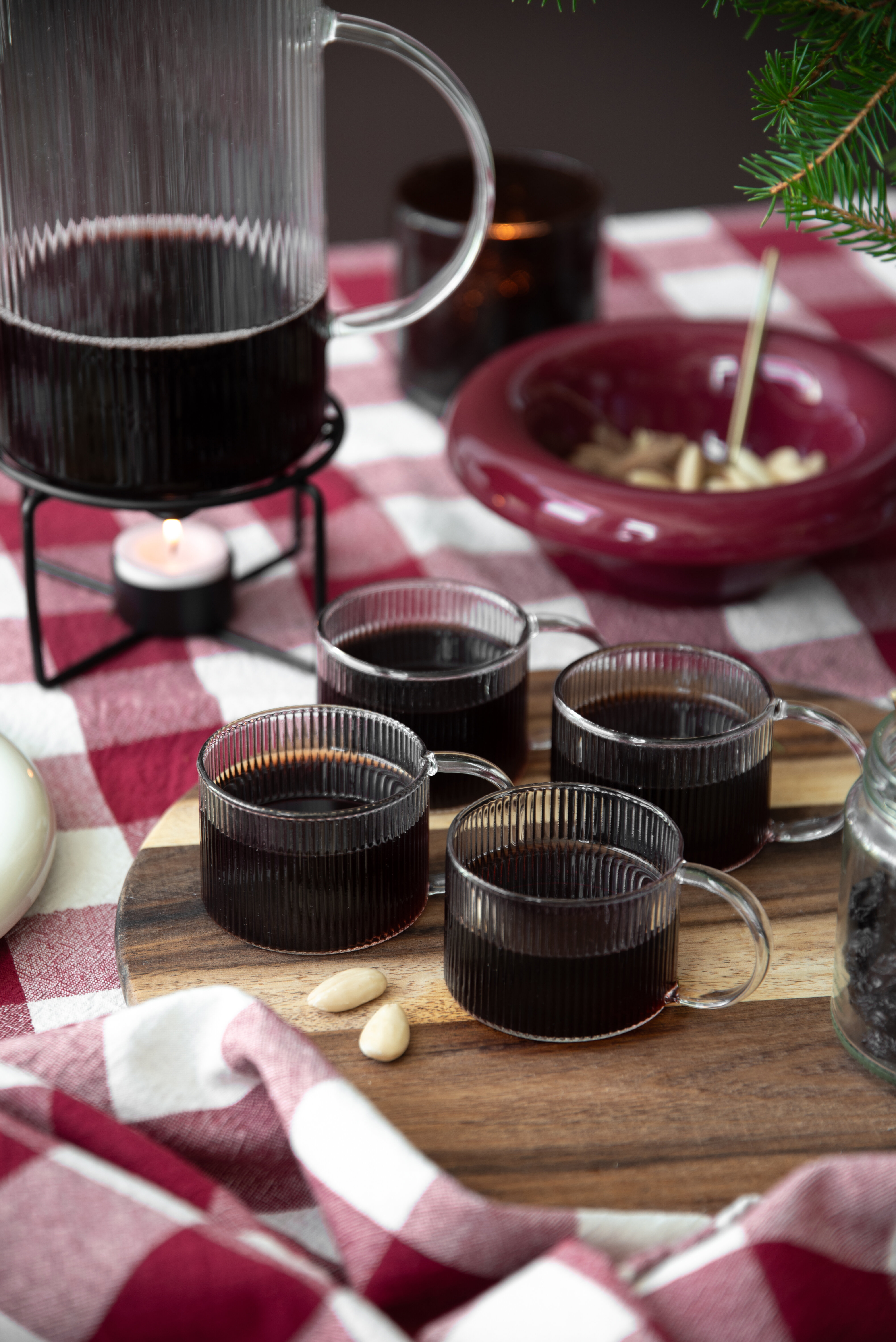 Mugs of mulled wine on a Christmas table setting in red tones.