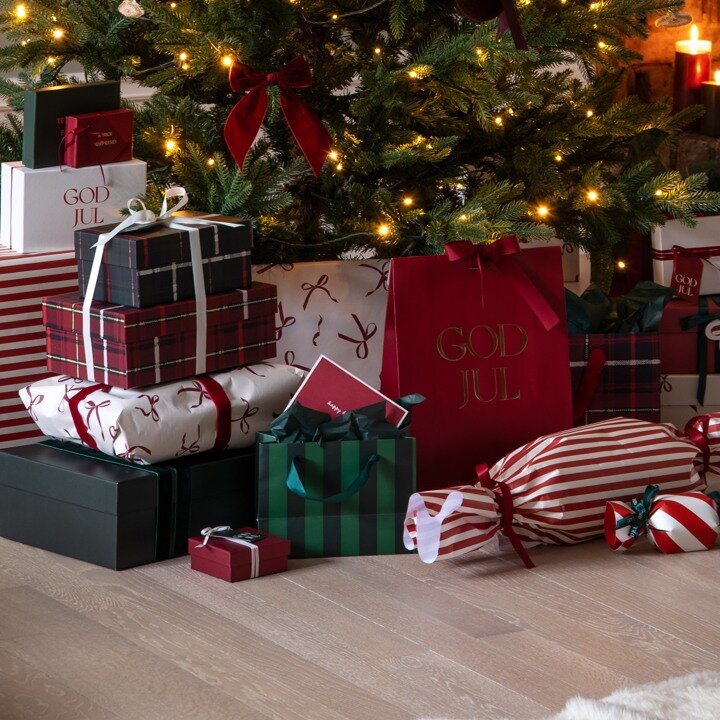 Wrapped Christmas gifts in different colours and patterns under a Christmas tree.