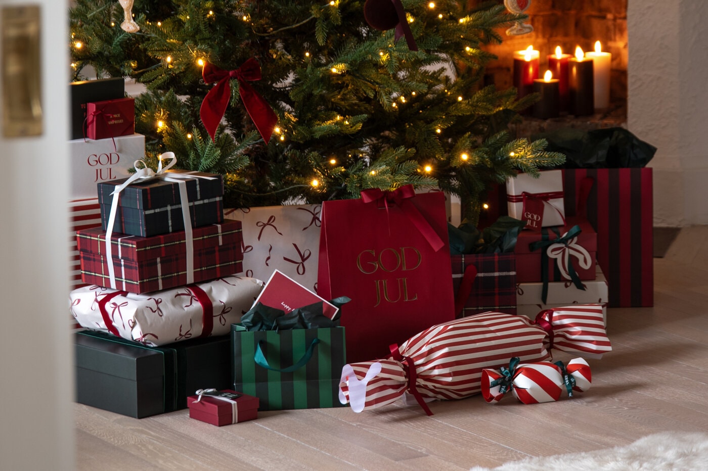 Wrapped Christmas gifts in red, green and tartan patterns under a decorated Christmas tree