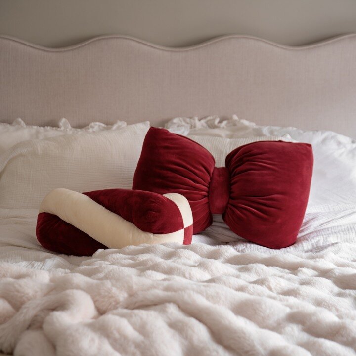 Red velvet cushions with bow designs on a bed.