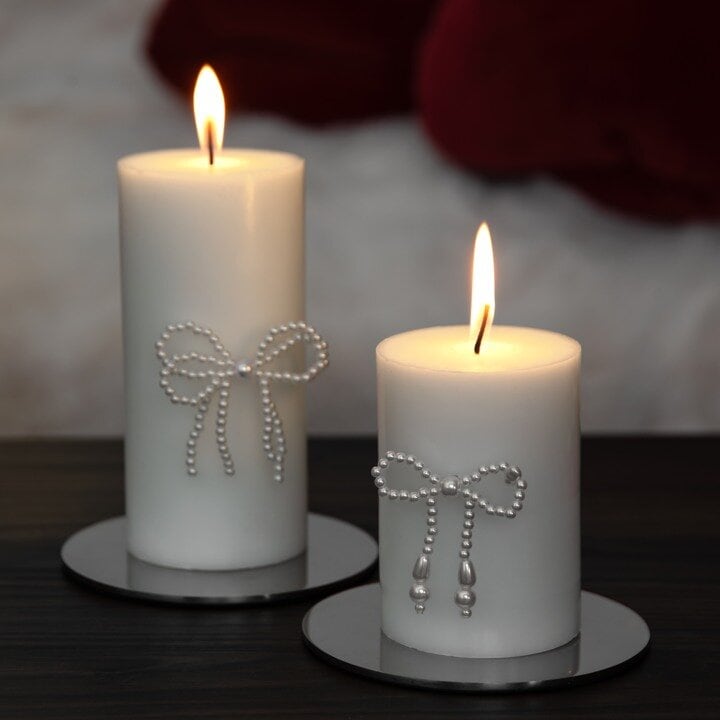 Lit white pillar candles with decorative bows.