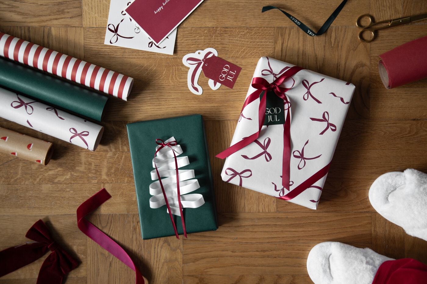 Wrapped Christmas gifts in green and white with red and white ribbons on a wooden table.