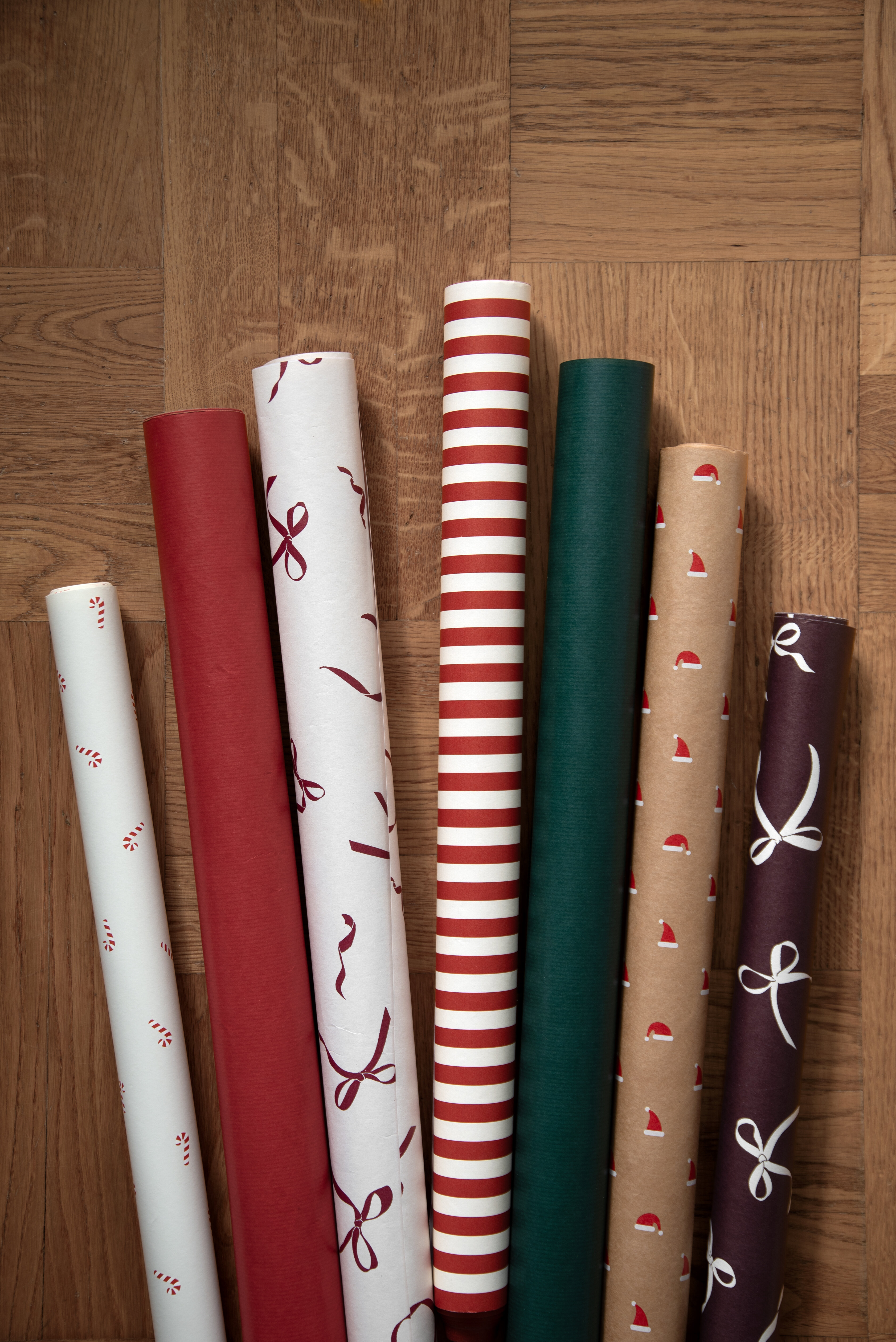 Rolls of Christmas wrapping paper in red, green, white and brown.