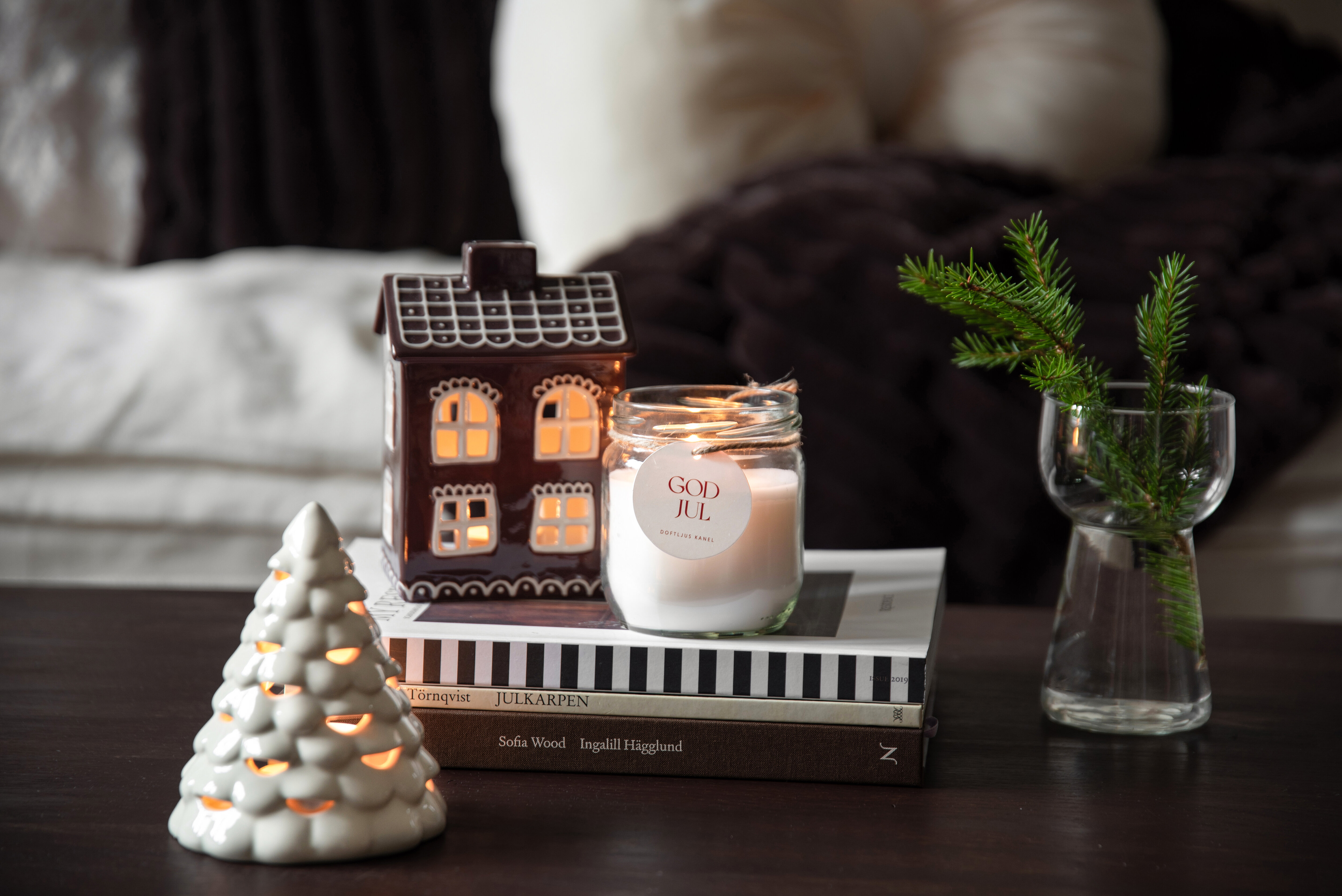Christmas decorations with lit candles, a gingerbread house and fir branches.