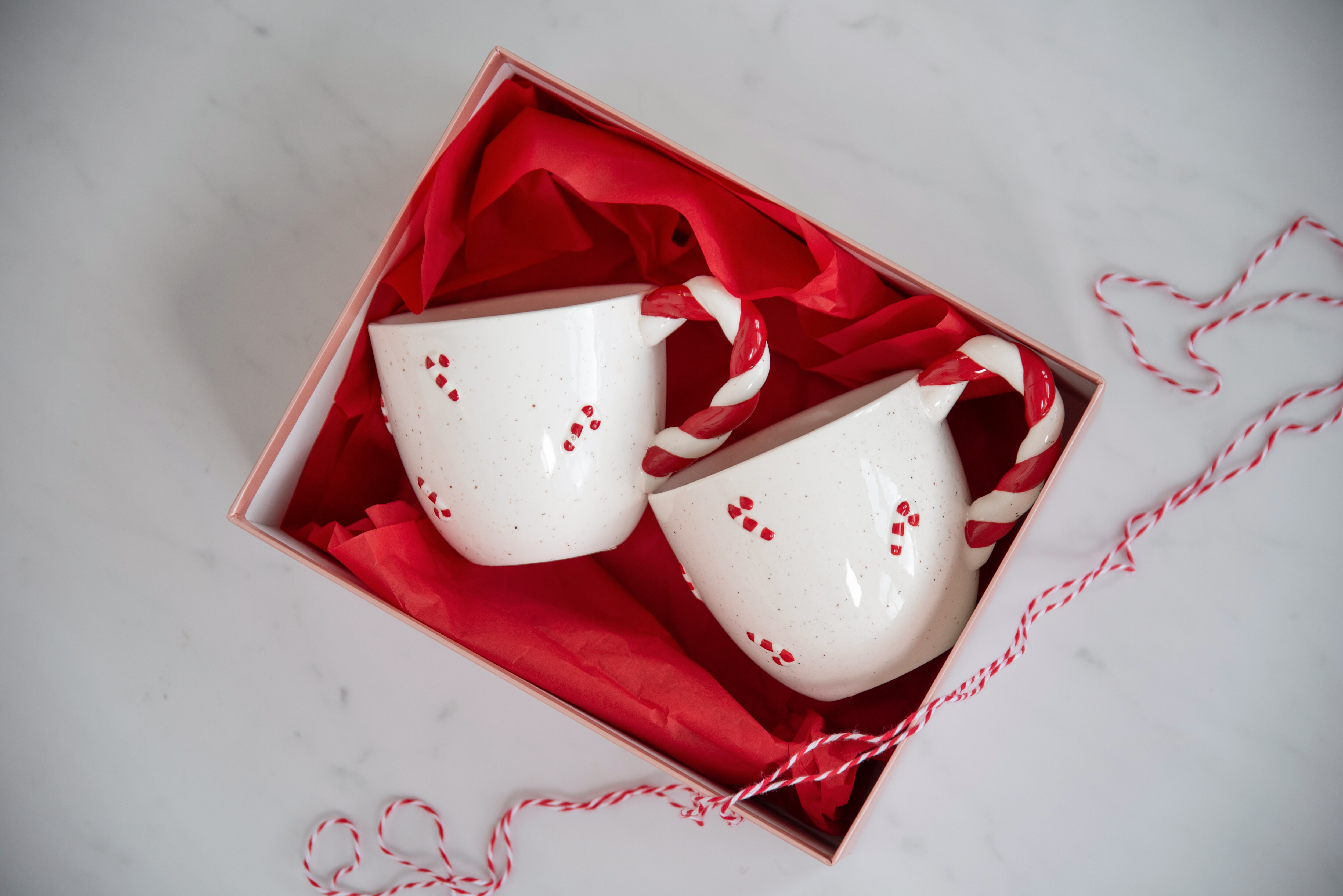 Several taper candles in different colors – red, green, white, and brown – placed on green tissue paper.