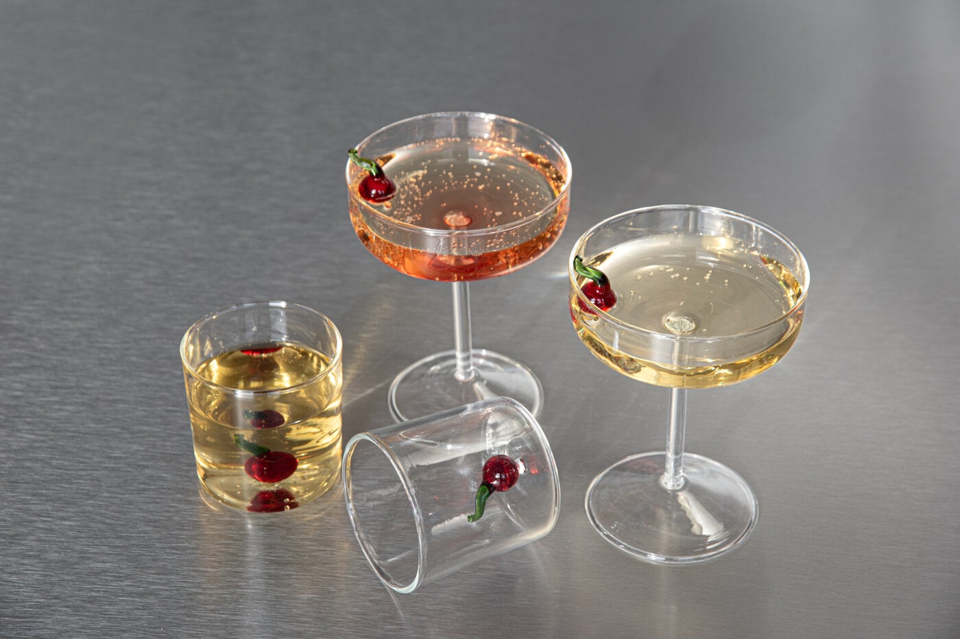 Cherry glasses and champagne glasses with decorative cherries, filled with drinks.
