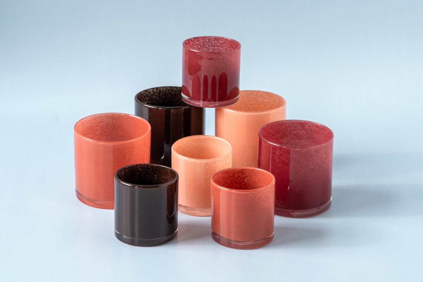 Tealight holders in glass in a group against blue background.