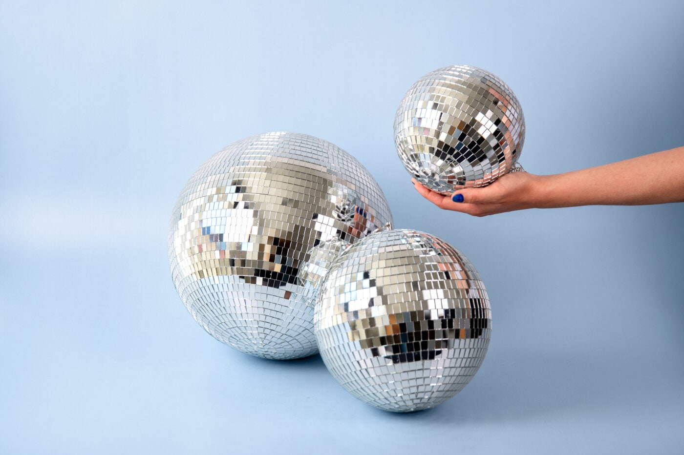 Silver-coloured disco balls against light blue background.