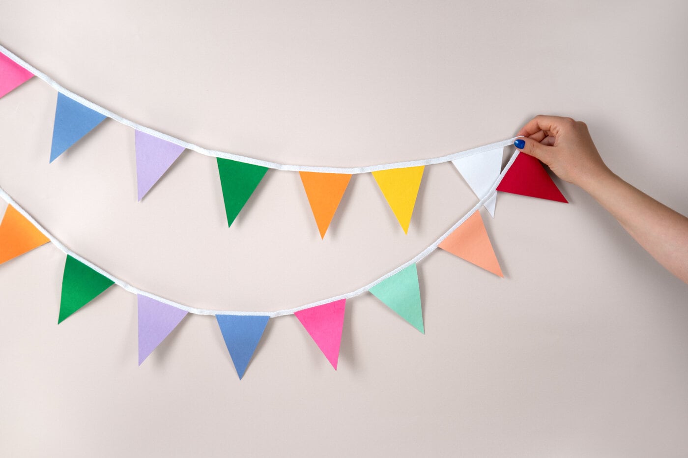 Colourful bunting with triangular flags in green, blue, pink, purple, yellow, orange, white and red.