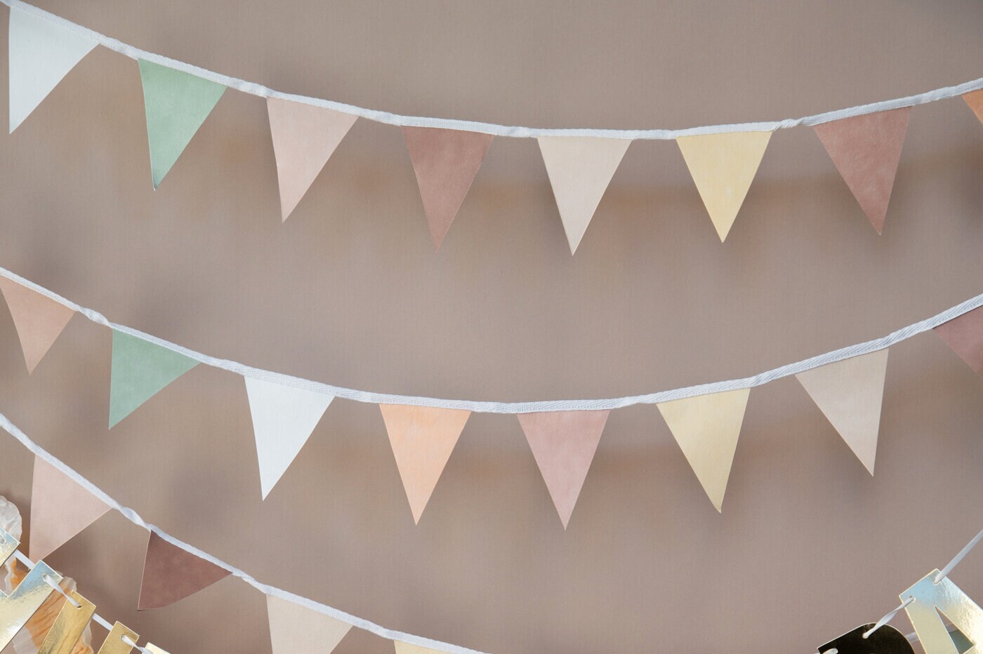 Neutral-coloured bunting hanging against a soft beige background.