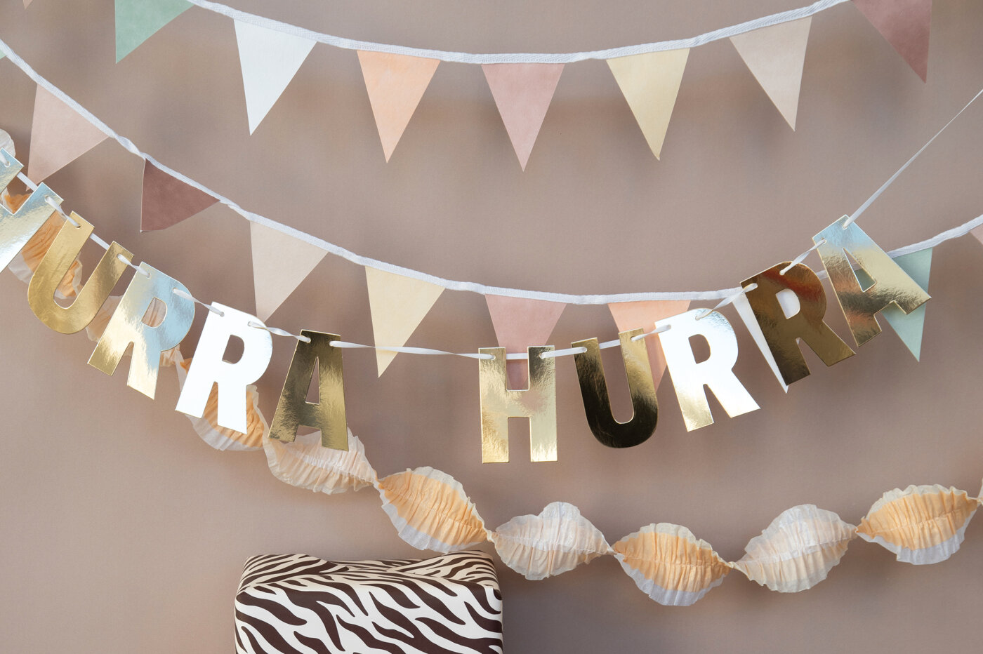 Garland in neutral tones and a gold-coloured garland with the text “hurra”
