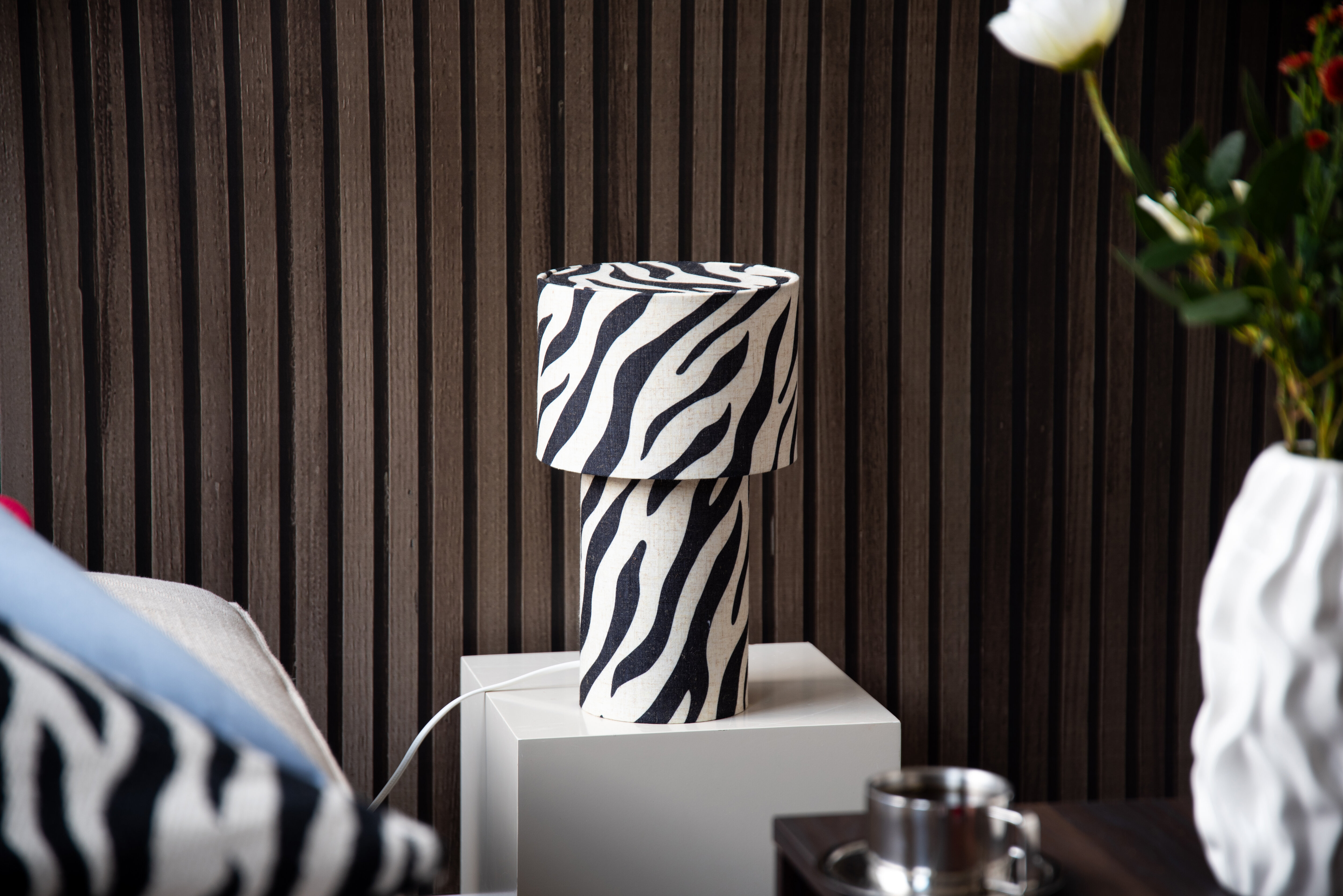 Decorative zebra-patterned table lamp against a dark wooden wall