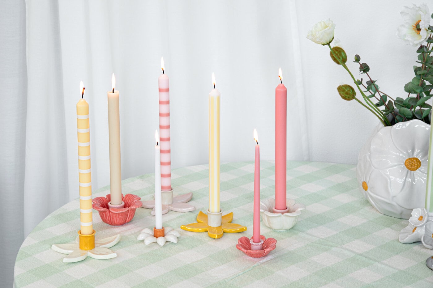 Pastel-coloured Easter candles in decorative candle holders on a set table