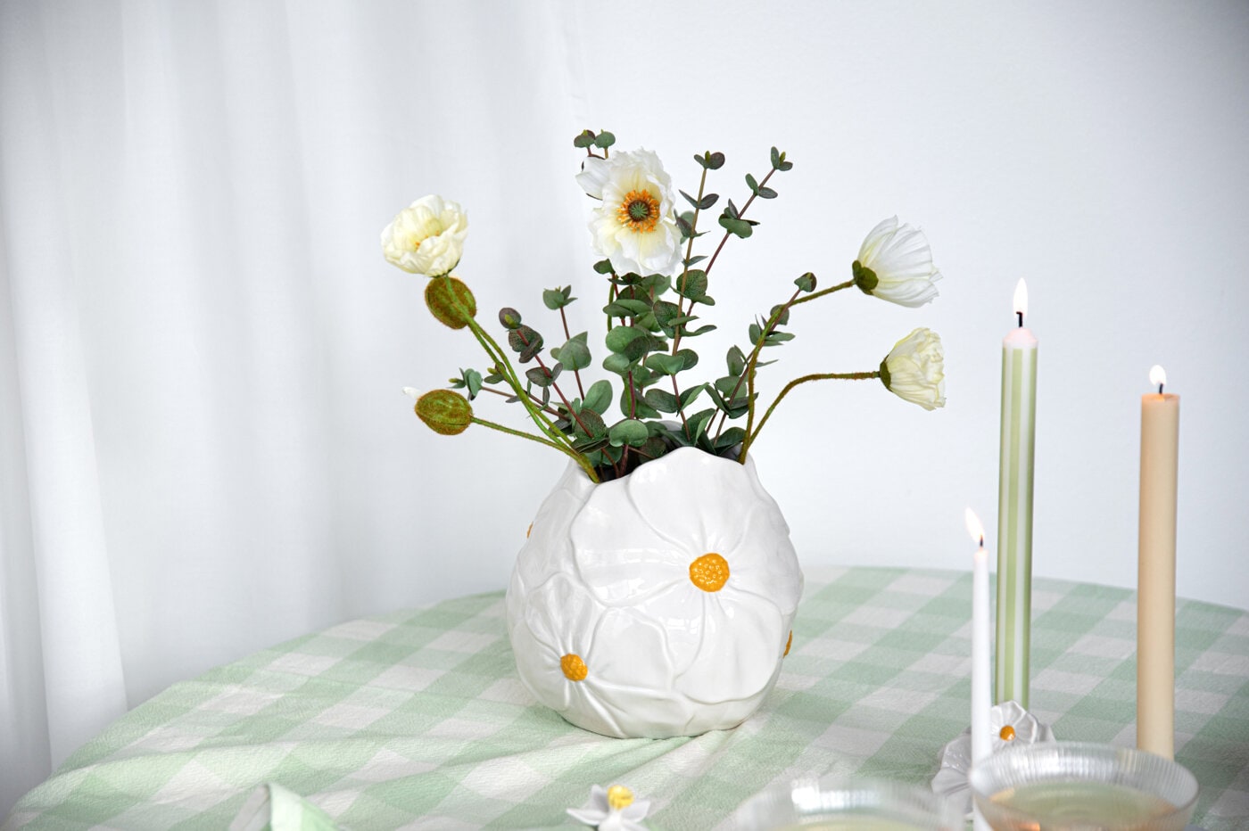 Vase with spring flowers and candles on a table