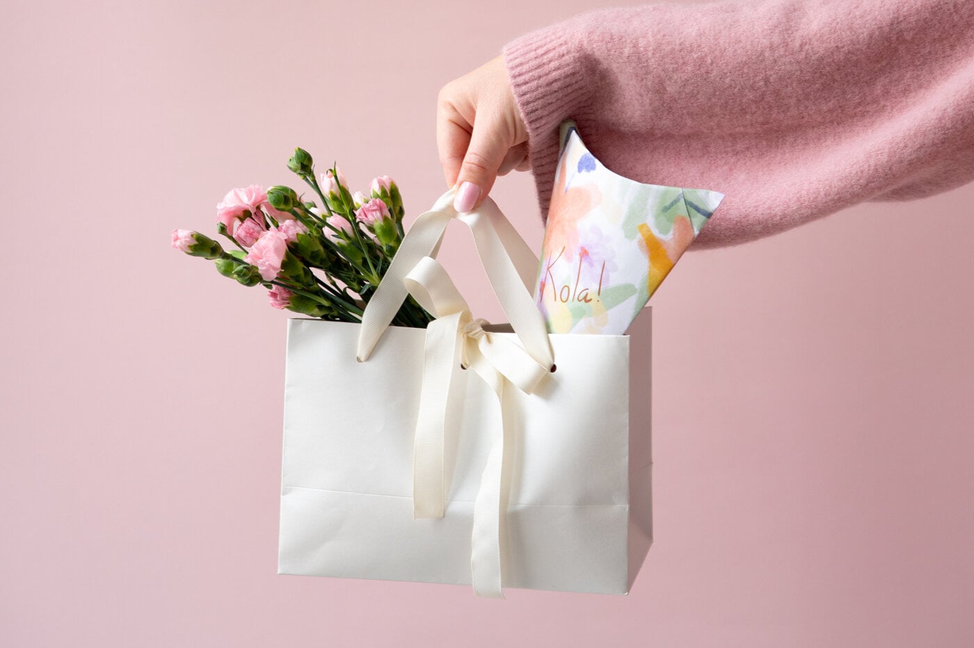 Inspiration image with a gift bag and flowers against a pink background.