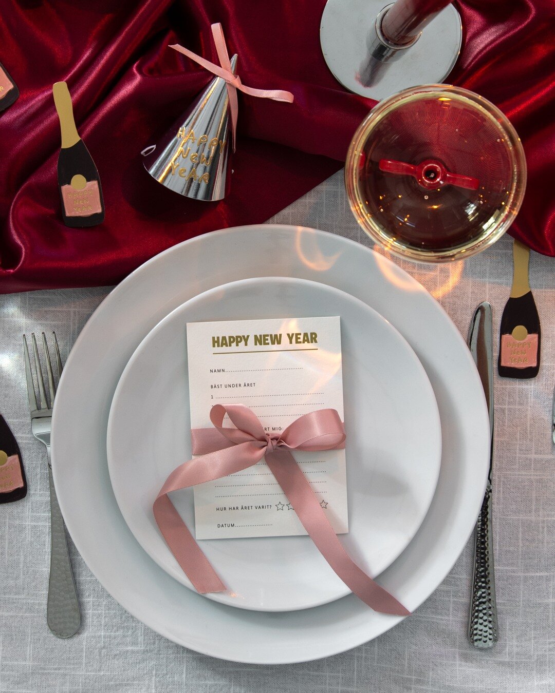 Nyårsdukning med tallrik, meny och rosett.
