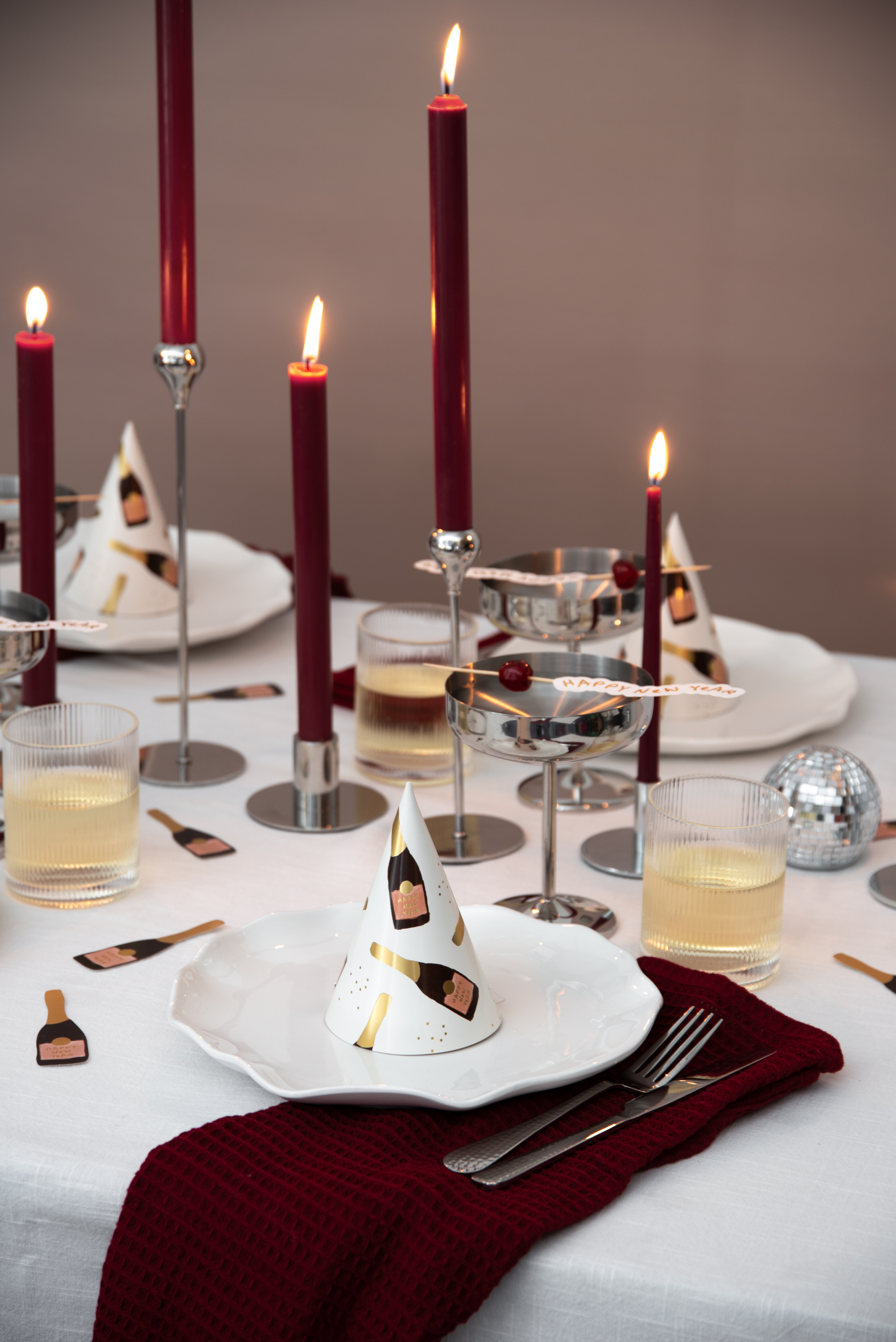 Röda ljus i silverljusstakar på dukat nyårsbord.