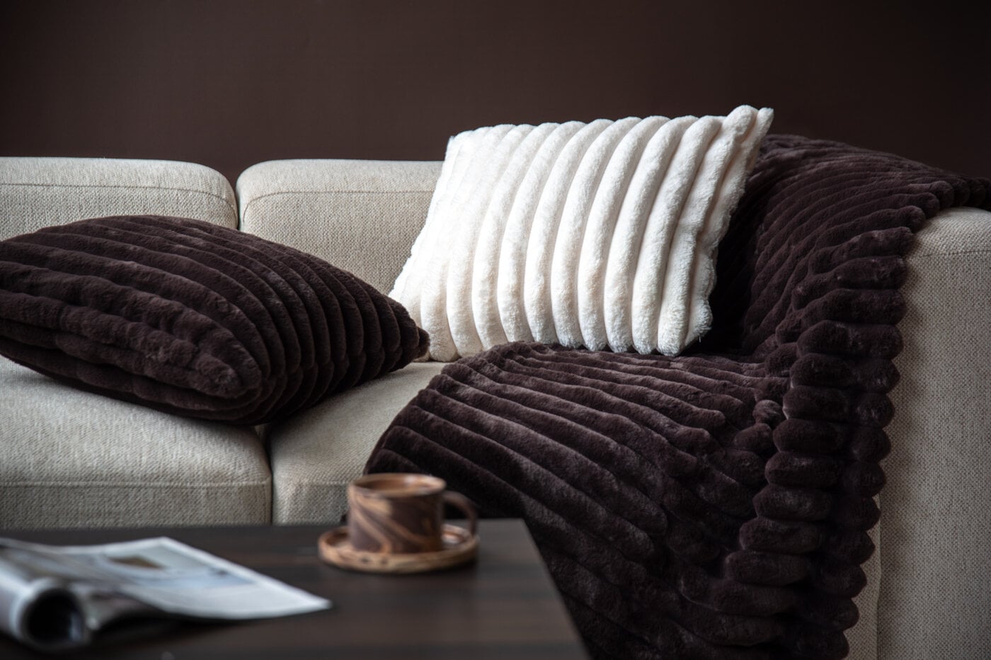 Light-coloured sofa with a dark brown throw and cushions in different colours.
