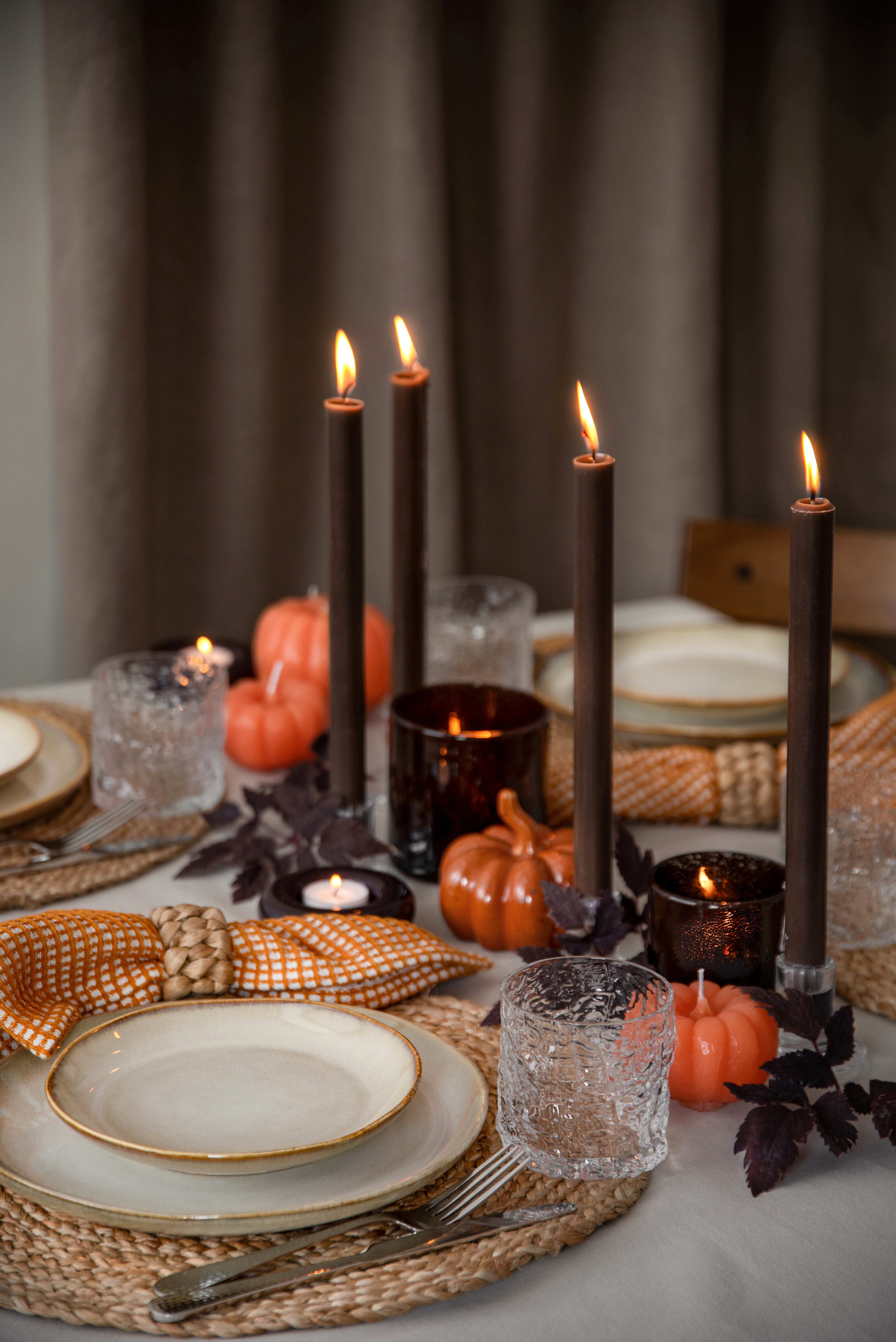 Autumn table setting with lit candles, pumpkins and warm seasonal details.