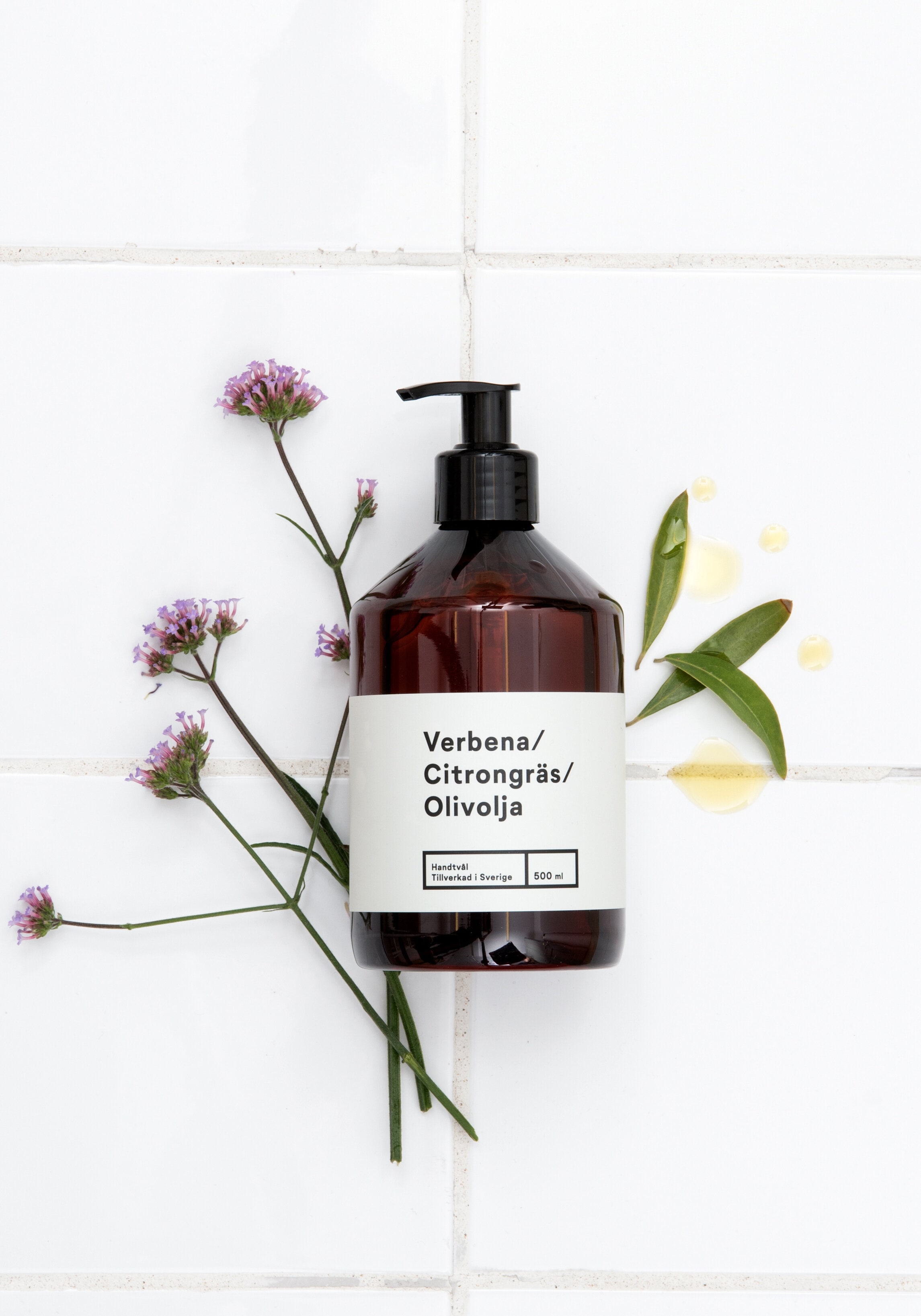 Tvål i mörka flaskor på stengolv.