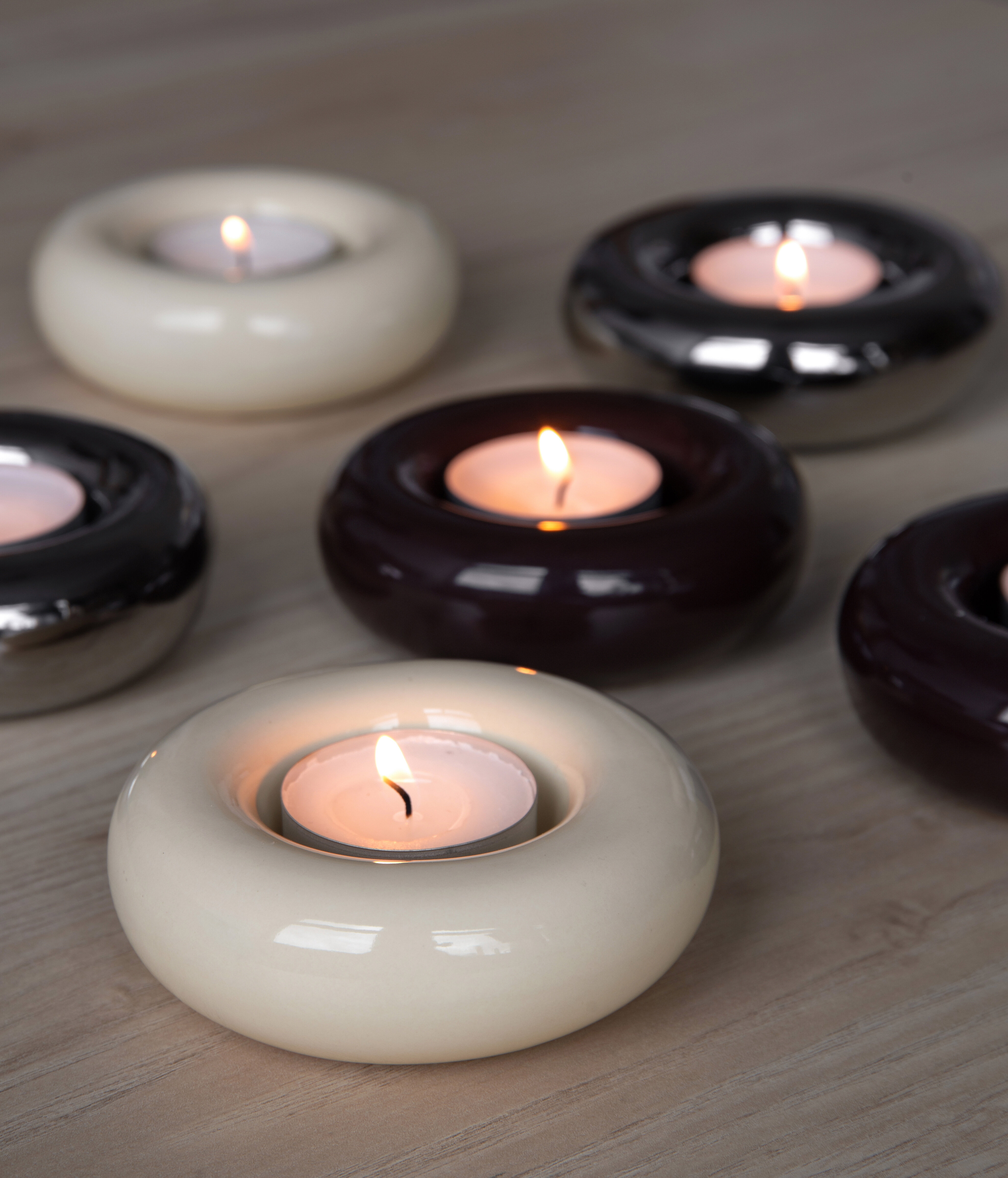 Round candle holders with lit tealights in different colours.