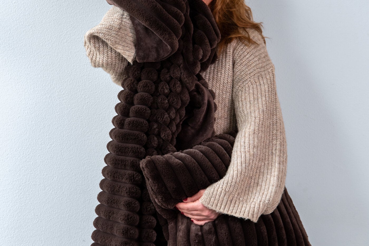 Person holding a brown soft blanket and pillow.