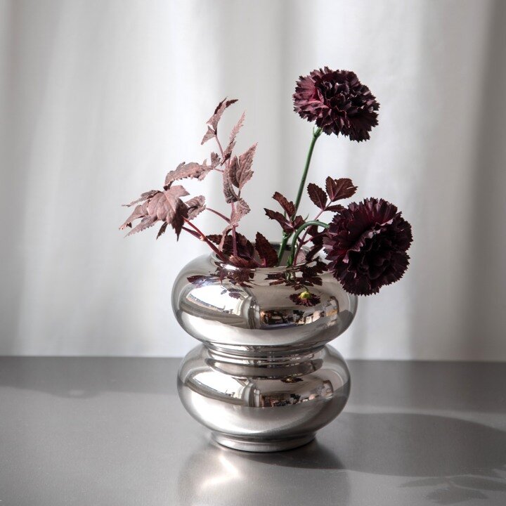 Silver coloured vase with artificial flowers.
