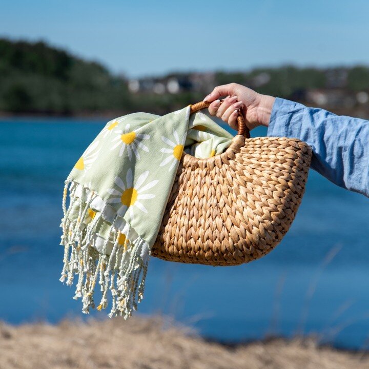 Straw beach bag with flowers by the sea.