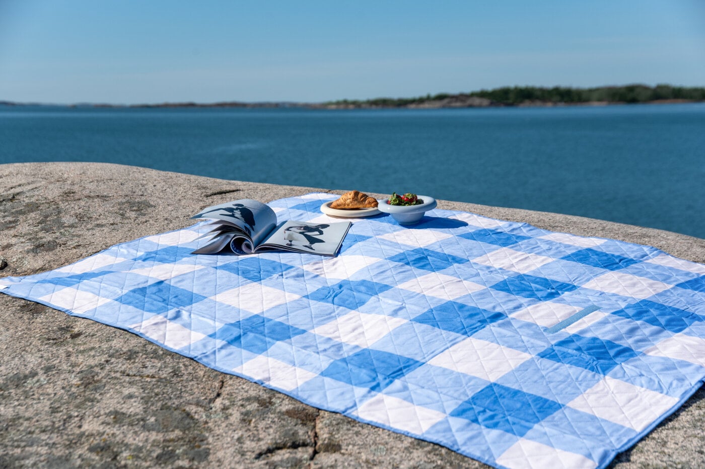Blue/white picnic blanket by the ocean.