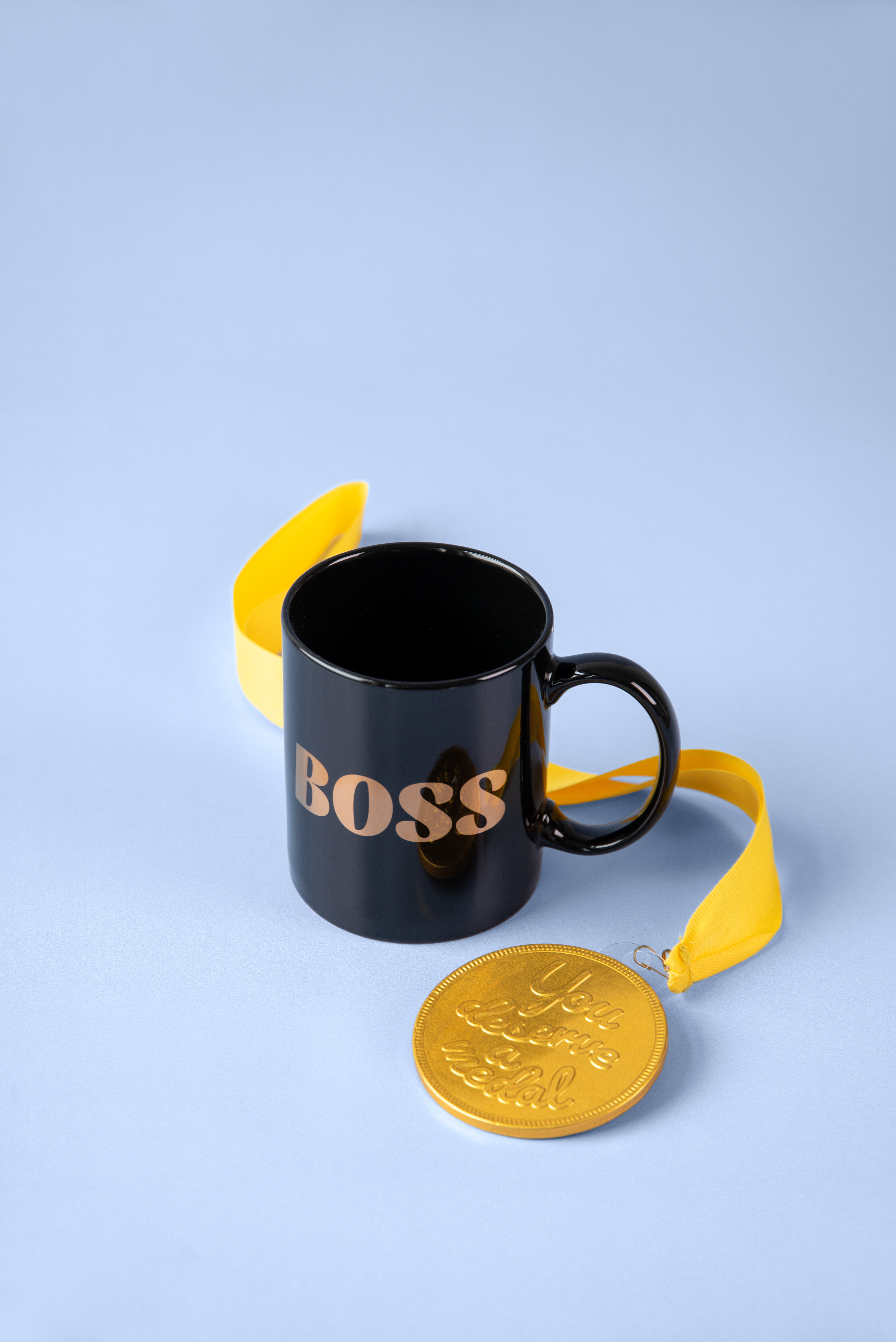 Black mug with “Boss” text next to lemon slices on a pastel background.