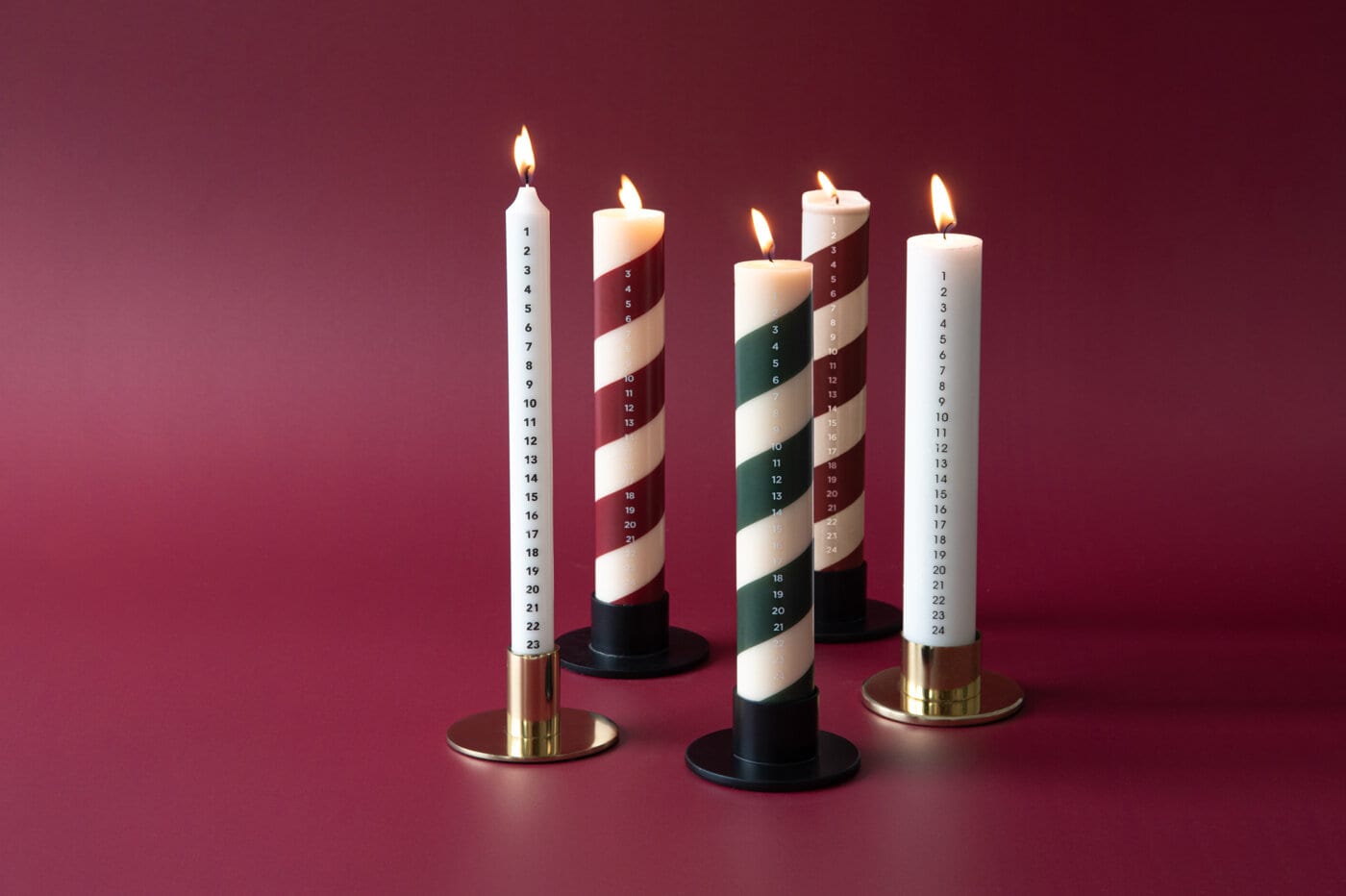 White candles tied together with string, placed on artificial snow.