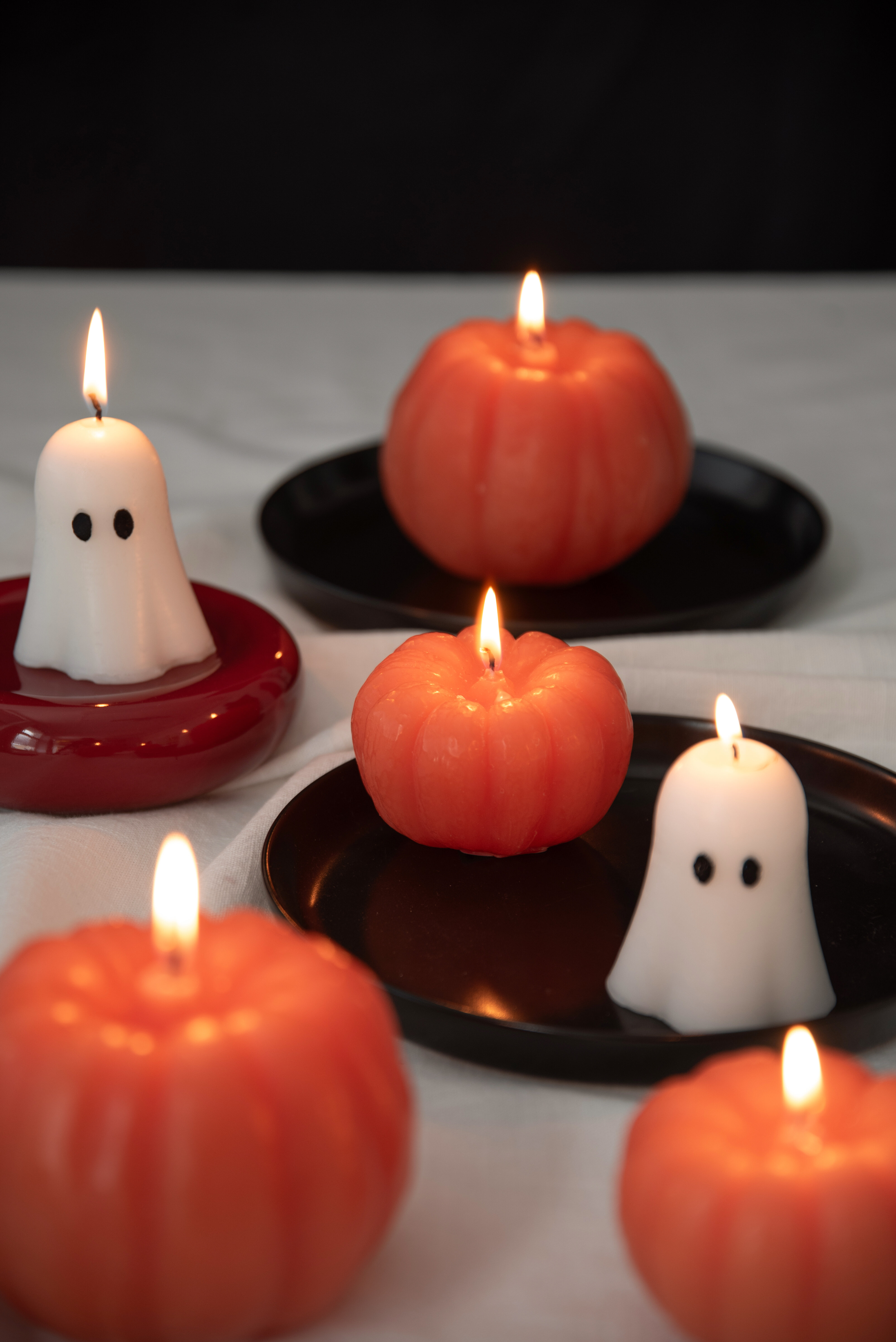 Lit candles shaped like pumpkins and ghosts.